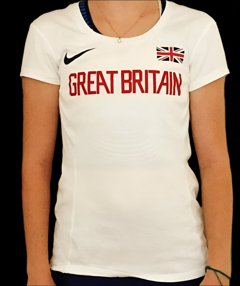 The athlete is wearing a Nike Great Britain Dri Fit tee with short sleeves. The shirt is predominantly white with the Nike logo and GB flag in each corner  and the 'Great Britain' team logo in red.